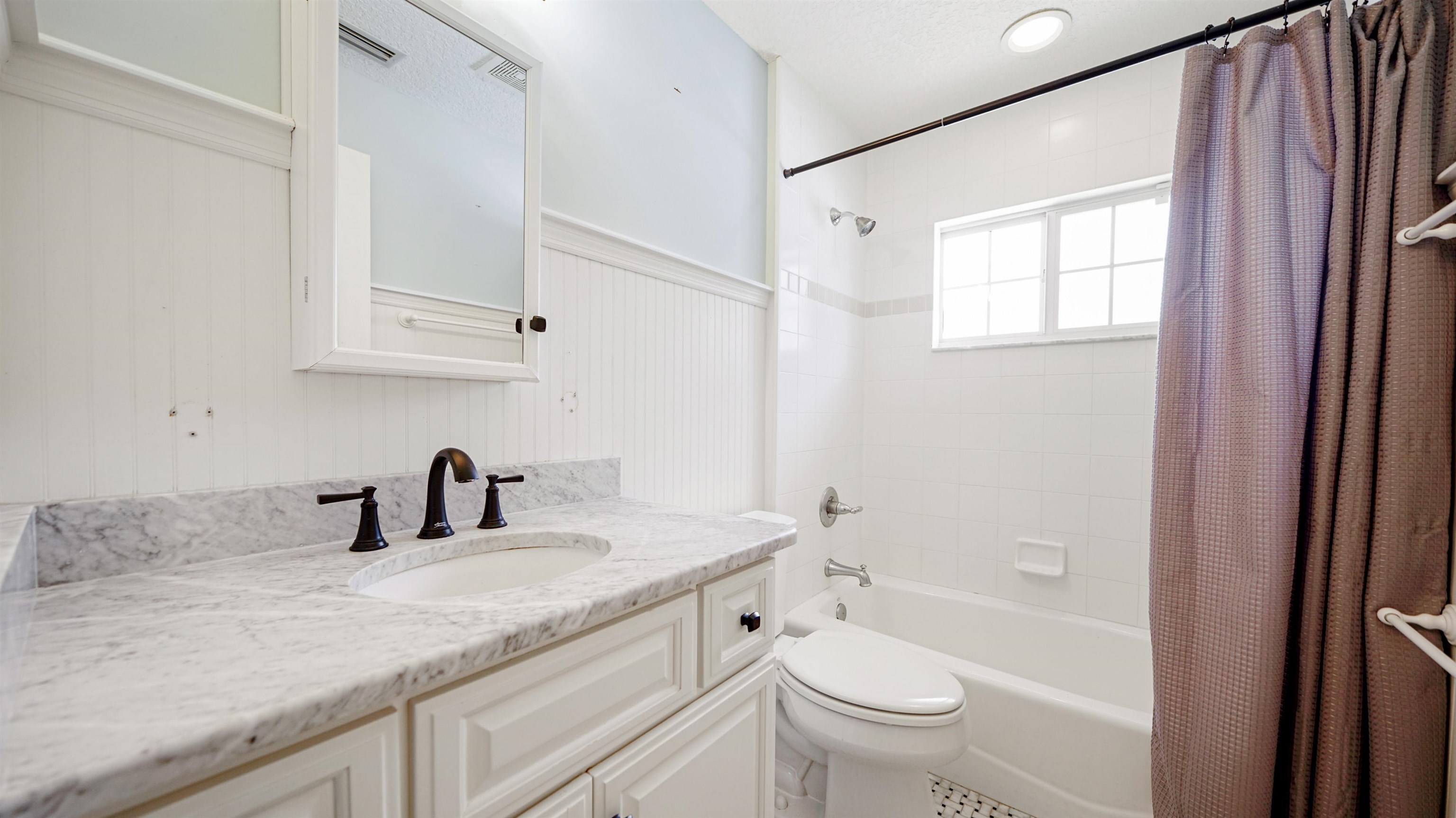 5324 5th Street St. Augustine, FL 32080 - Photo 27 of 49 a bathroom with a granite countertop sink a toilet and a mirror