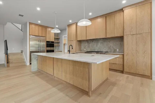 a view of a kitchen with kitchen island a sink stainless steel appliances and cabinets