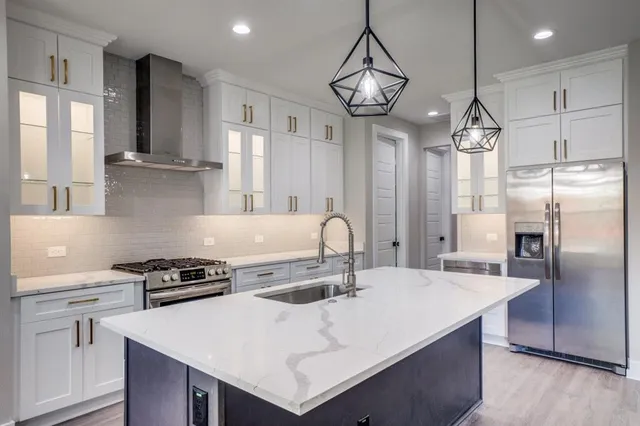 a kitchen with stainless steel appliances a table a sink and refrigerator