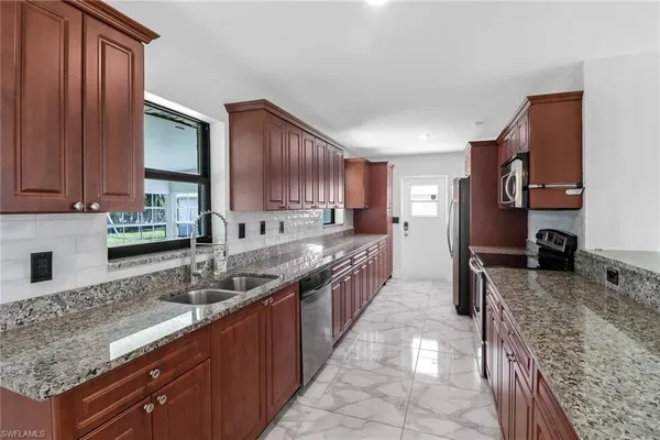 a large kitchen with granite countertop a sink stove and cabinets