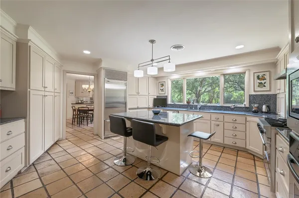 a large white kitchen with a window and stainless steel appliances