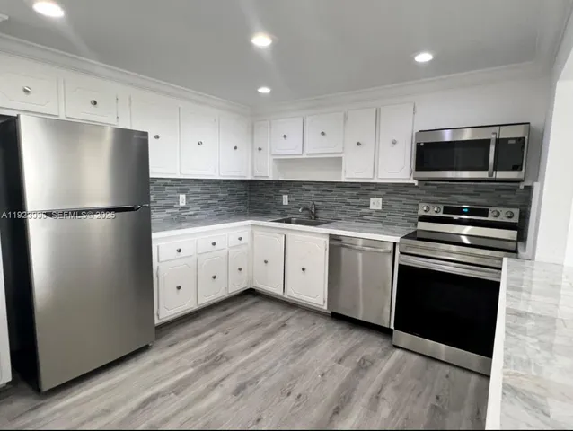 a kitchen with cabinets stainless steel appliances and wooden floor