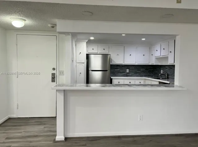 a view of kitchen with stainless steel appliances granite countertop cabinets and wooden floor