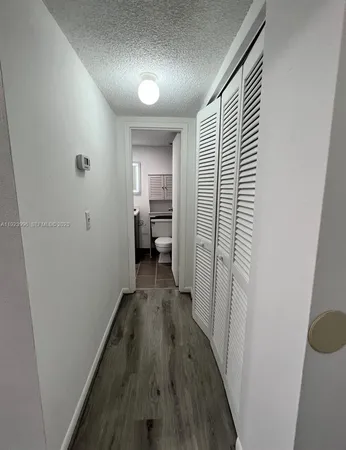 a view of a hallway with wooden floor windows and a bathroom
