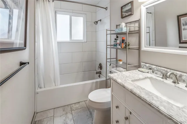 a bathroom with a granite countertop sink a toilet and shower