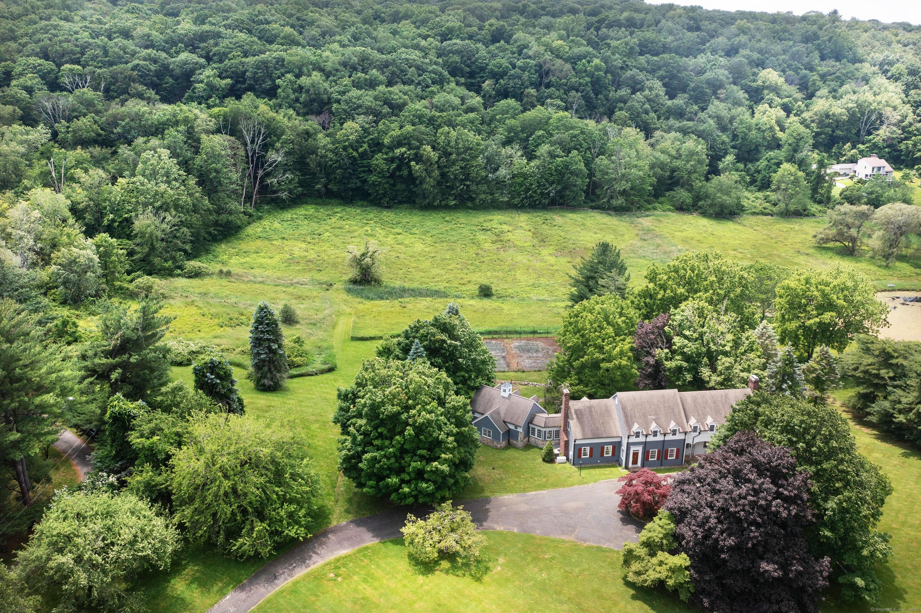an aerial view of residential house with outdoor space and trees all around