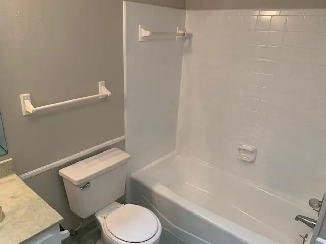 a white toilet and tub sitting next to a bathroom sink