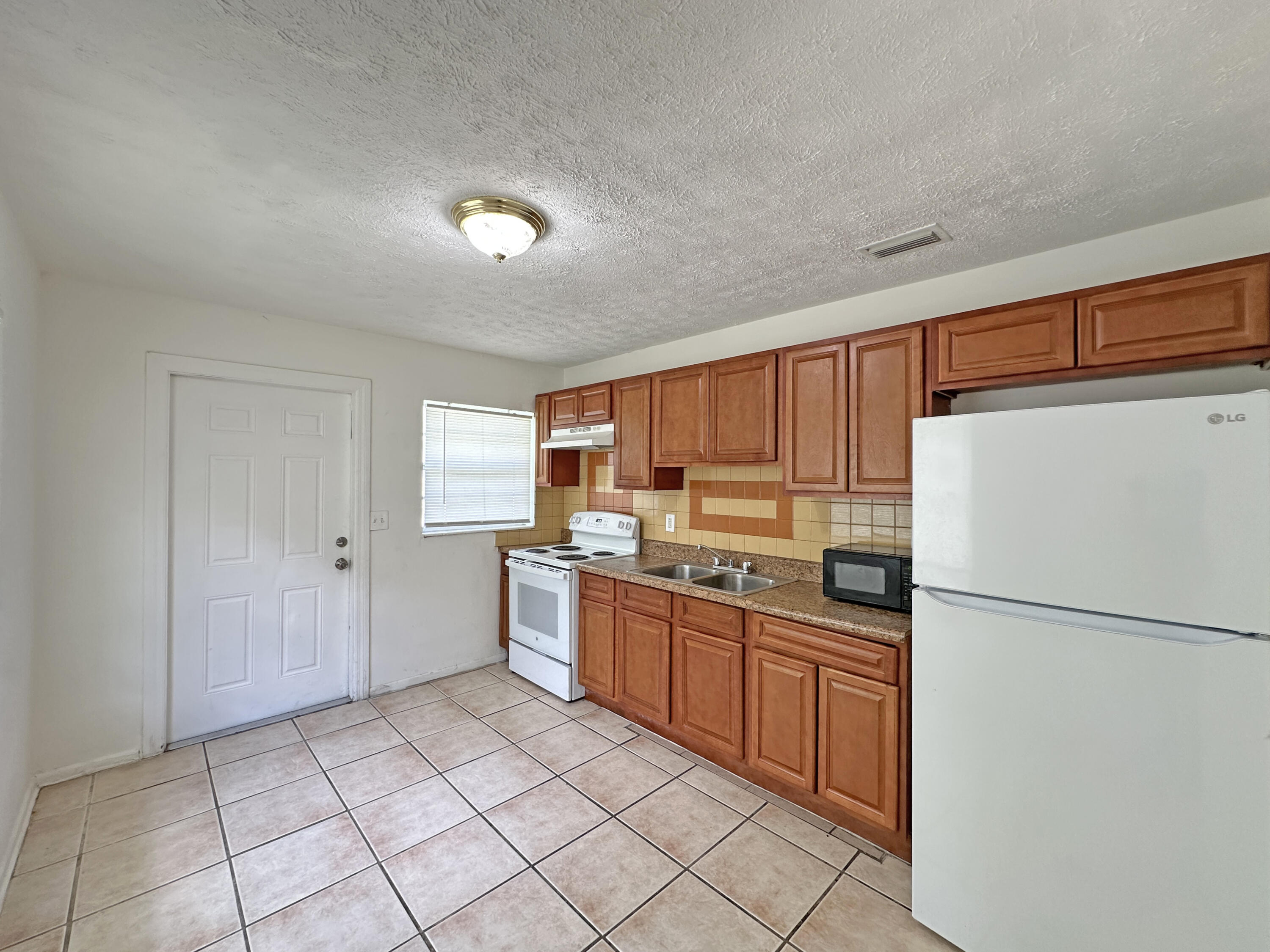 1107 North 21st Street, Unit A & B Fort Pierce, FL 34950 - Photo 17 of 24 a kitchen with a refrigerator a stove top oven and cabinets