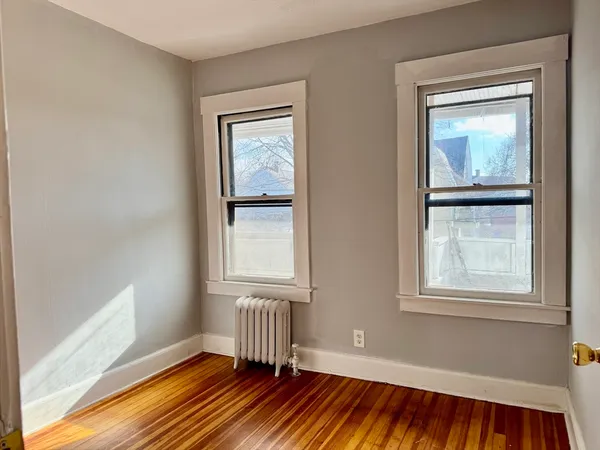 a view of an empty room with a window and wooden floor