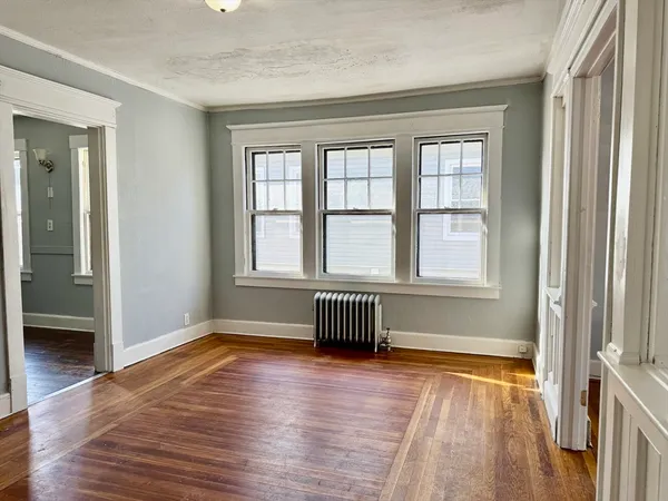 a view of an empty room with wooden floor and a window