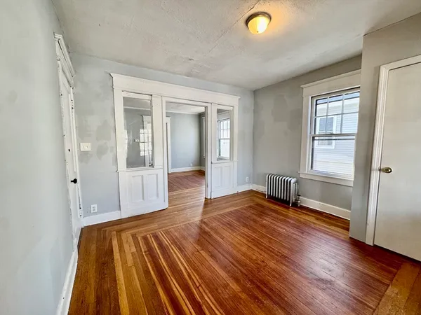 a view of an empty room with wooden floor and a window