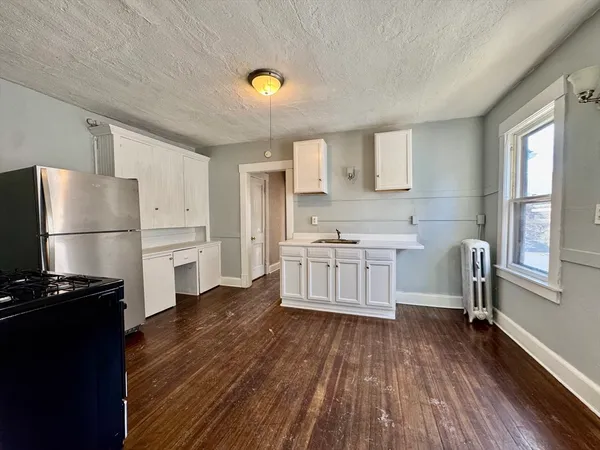 a kitchen with white cabinets and wooden floor