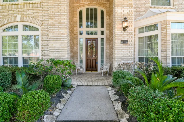 front view of a brick house with a large windows and potted plants