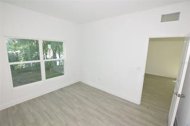 an empty room with wooden floor and windows