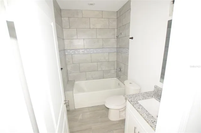 a bathroom with a granite countertop bathtub shower and toilet