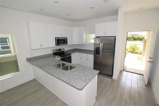 a kitchen with granite countertop a refrigerator and a stove top oven
