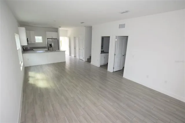 a view of a kitchen with a fridge and wooden floor
