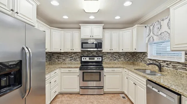 a kitchen with granite countertop white cabinets and stainless steel appliances