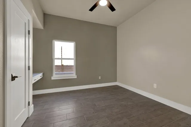 an empty room with chandelier fan and windows