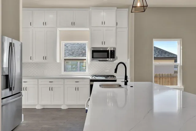 a kitchen with stainless steel appliances a sink a stove and white cabinets