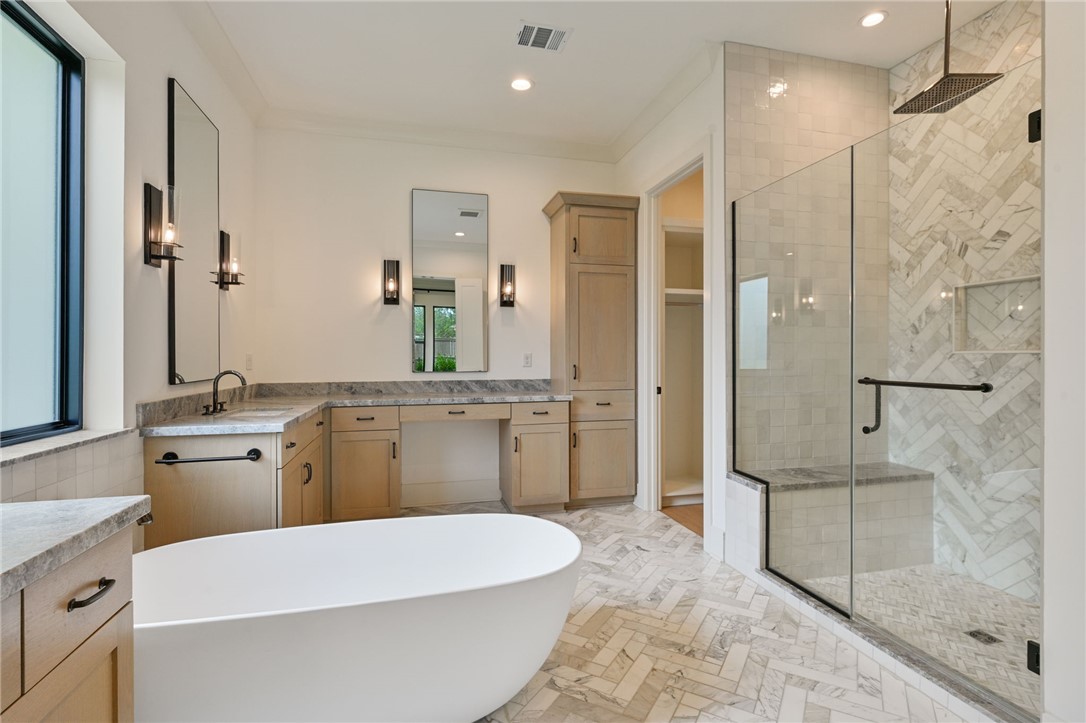 5115 Inverness Drive Bryan, TX 77802 - Photo 14 of 28 Freestanding soaking tub with a spacious glass-enclosed shower featuring a bench and herringbone-patterned tile