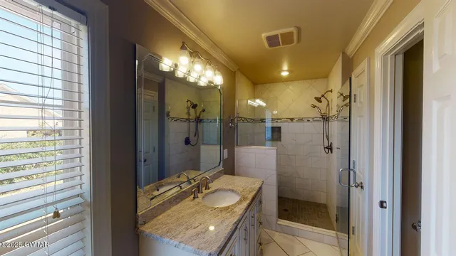 a bathroom with a granite countertop sink mirror and shower