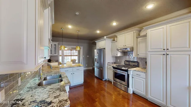 a kitchen with granite countertop kitchen island stainless steel appliances a stove a sink and a refrigerator