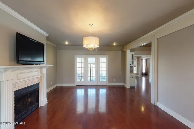 a view of an empty room with wooden floor fireplace and a window