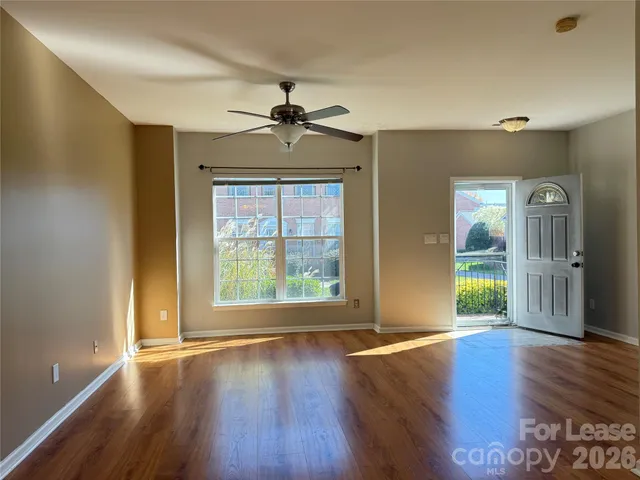 a view of an empty room with window and wooden floor