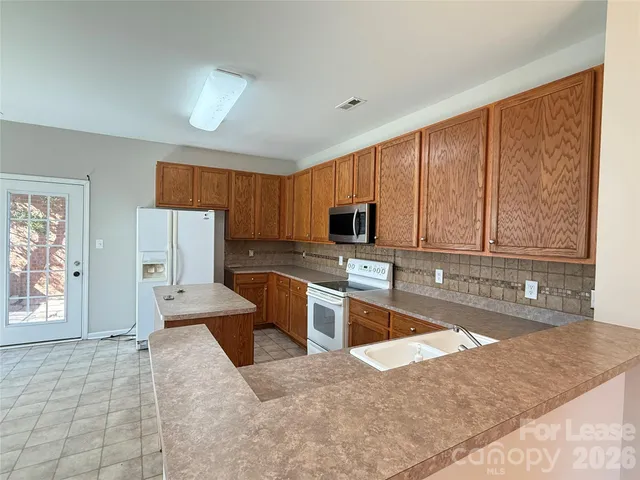 a large kitchen with stainless steel appliances granite countertop a refrigerator sink and cabinets