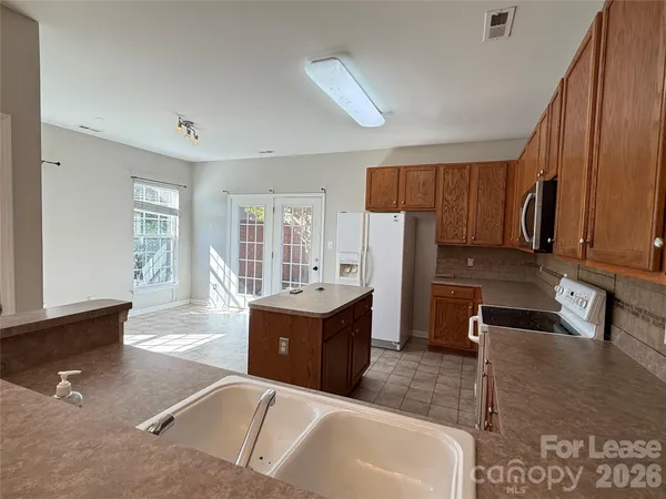 a large kitchen with kitchen island a large counter top space a sink a window and stainless steel appliances
