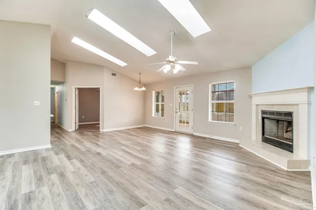 a view of an empty room with window and wooden floor