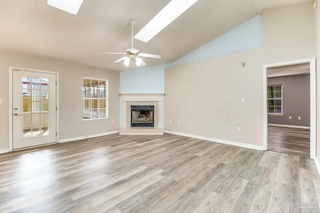 an empty room with wooden floor fireplace and windows