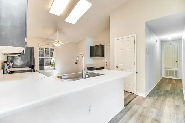 a large white kitchen with a sink and a large mirror next to a window