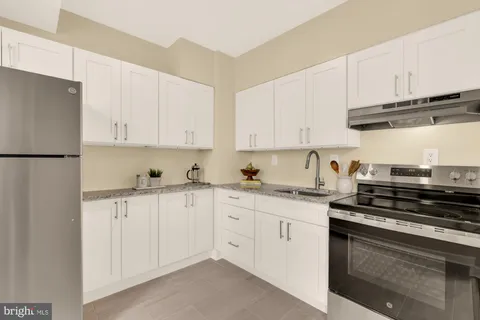 a kitchen with stainless steel appliances granite countertop white cabinets sink and stove