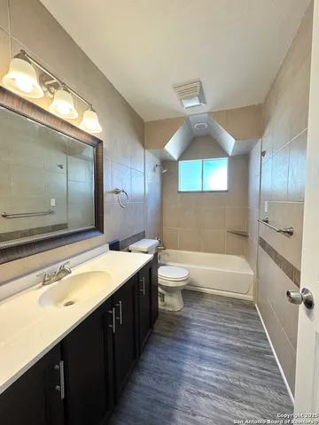a bathroom with a large tub sink vanity and a large mirror