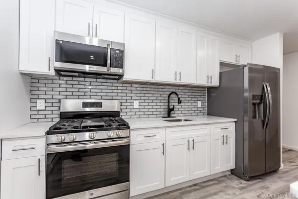 a kitchen with stainless steel appliances granite countertop a stove a refrigerator and a microwave