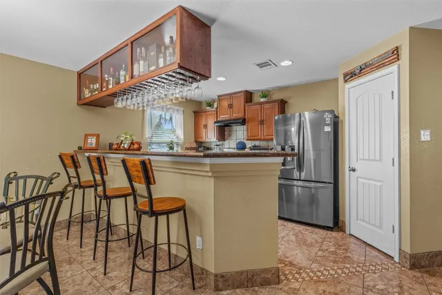 a kitchen with stainless steel appliances kitchen island granite countertop a refrigerator a stove a sink and a dining table with wooden cabinet