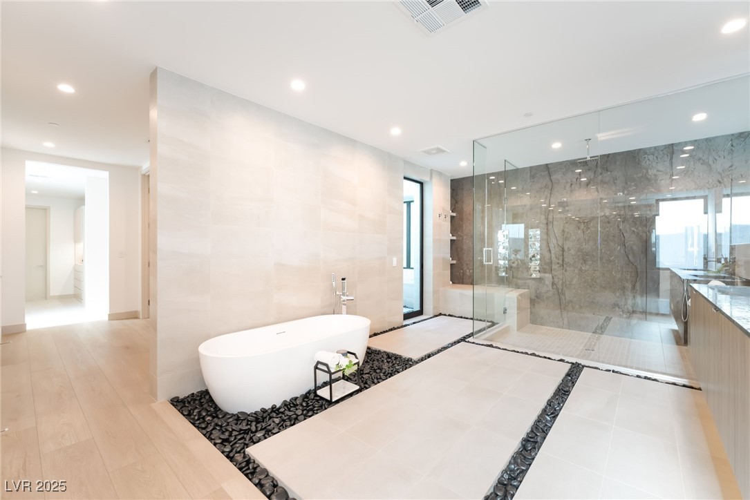 33 Falling Ridge Lane Henderson, NV 89011 - Photo 18 of 70 Full bathroom with a freestanding bath, tile walls, recessed lighting, a marble finish shower, and vanity