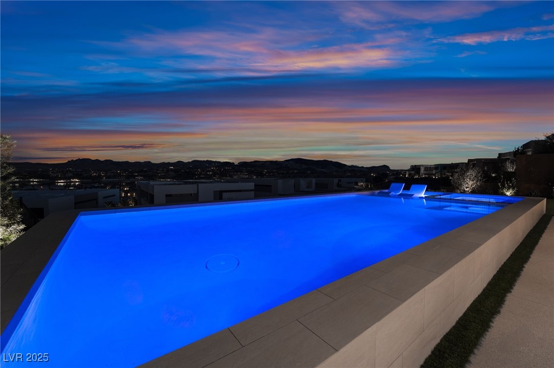 33 Falling Ridge Lane Henderson, NV 89011 - Photo 49 of 70 Pool at dusk with a patio area, an infinity pool, and a jacuzzi