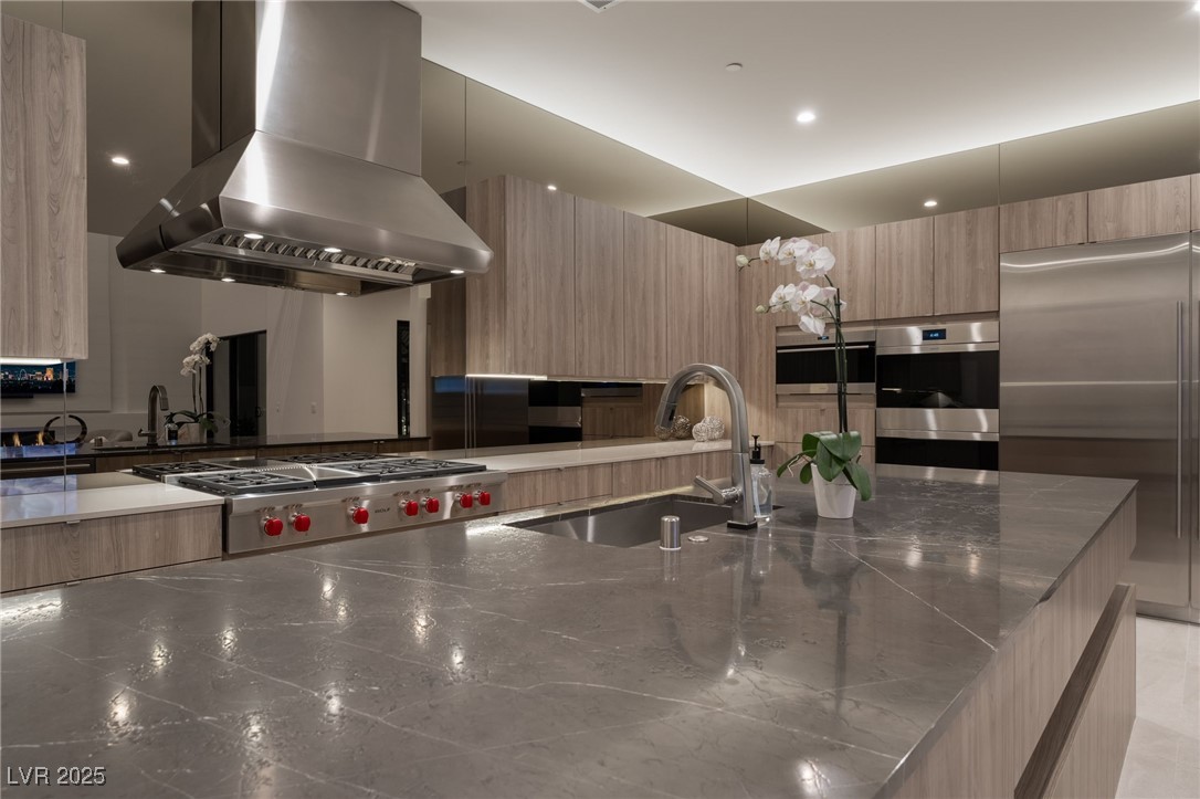 33 Falling Ridge Lane Henderson, NV 89011 - Photo 55 of 70 Kitchen featuring modern cabinets, island range hood, stainless steel appliances, dark stone countertops, and light brown cabinetry