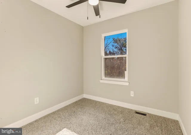 an empty room with a window and a ceiling fan