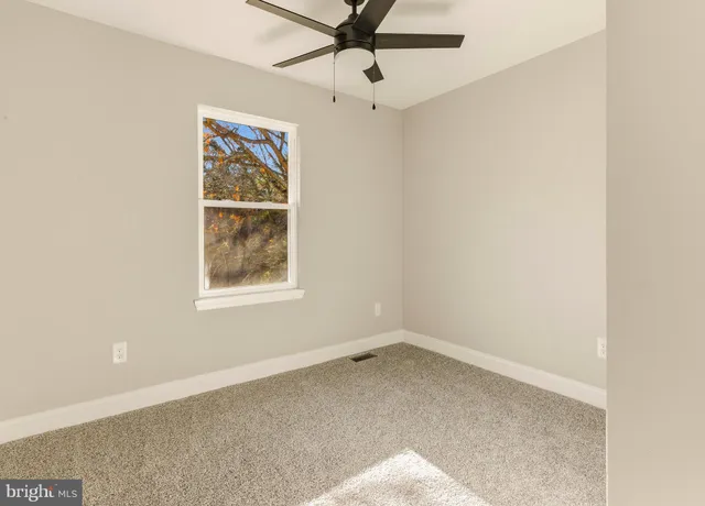 an empty room with a window and a fan