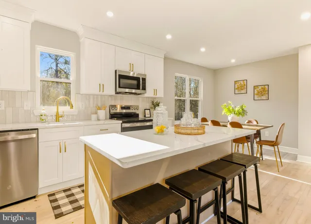 a kitchen with stainless steel appliances kitchen island granite countertop a sink a stove a dining table and chairs