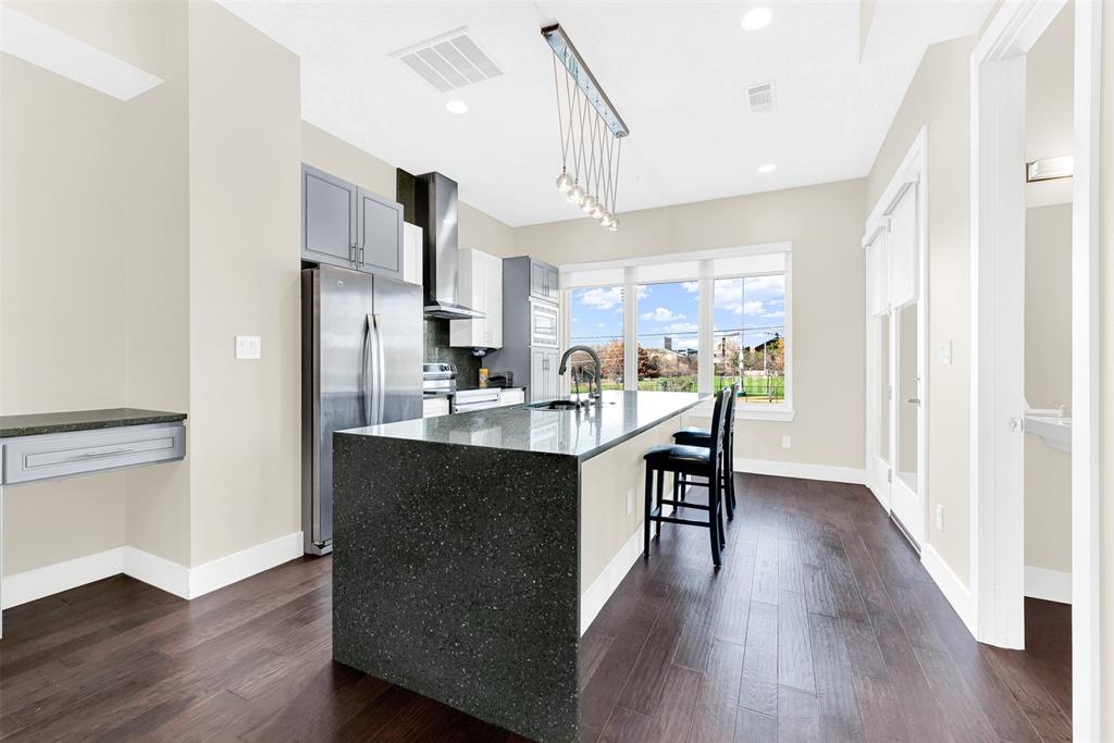 4060 Spring Valley Road, Unit 105 Farmers Branch, TX 75244 - Photo 6 of 19 a kitchen with stainless steel appliances granite countertop a refrigerator a sink dishwasher a stove and white cabinets with wooden floor