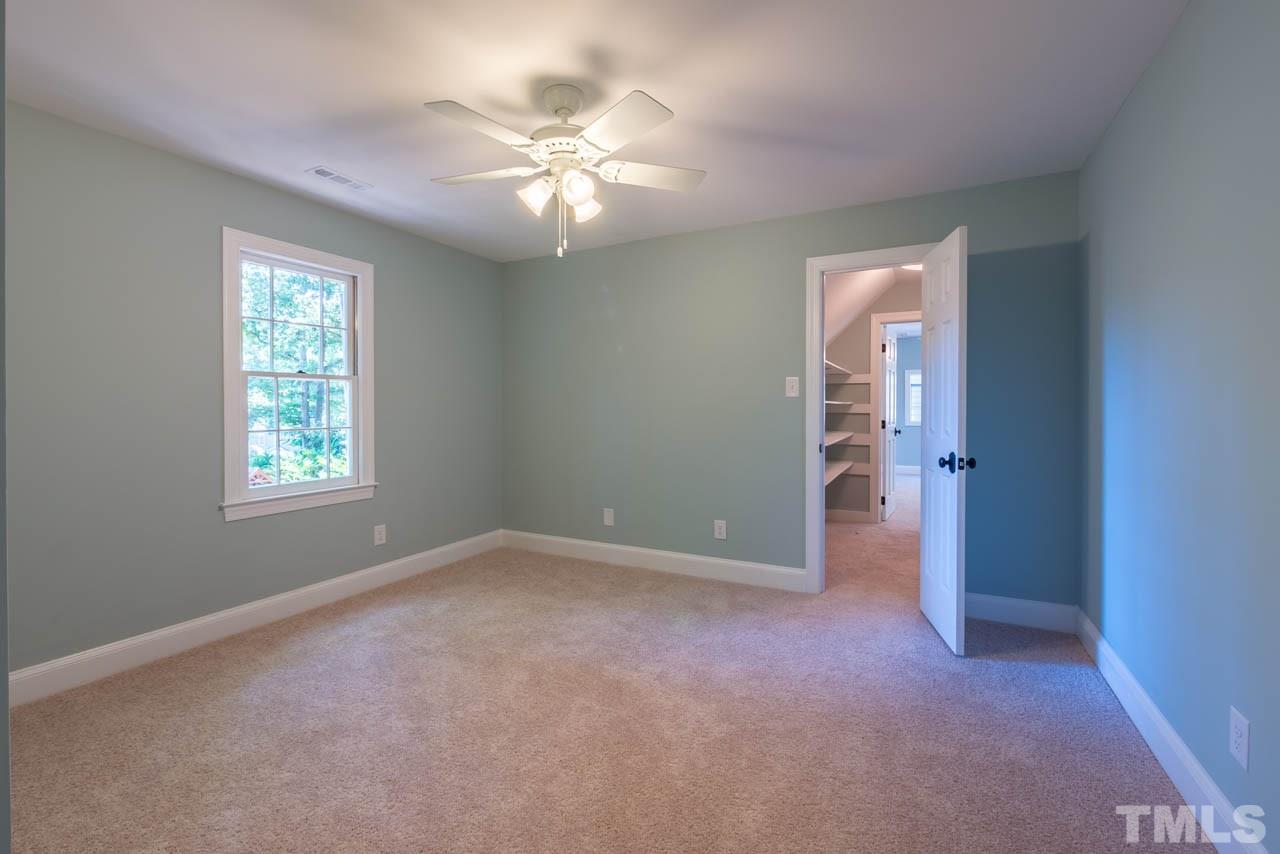 7405 Wilderness Road Raleigh, NC 27613 - Photo 14 of 25 an empty room with windows and chandelier fan