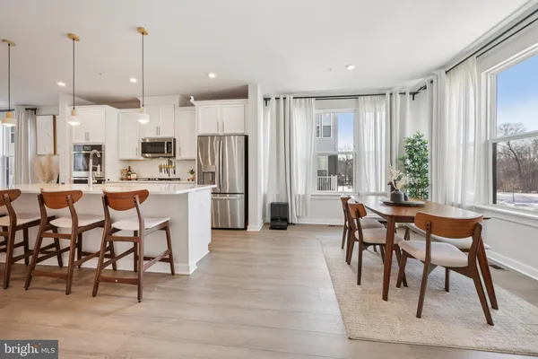 a dining hall with stainless steel appliances kitchen island granite countertop a table chairs and a refrigerator