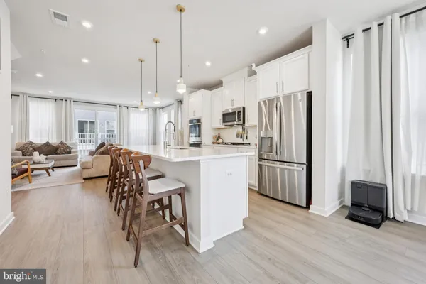 a kitchen with stainless steel appliances a refrigerator a stove a sink dishwasher a dining table and chairs with wooden floor