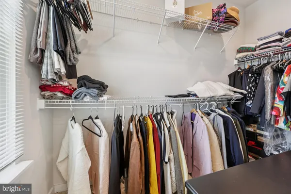a view of walk in closet with clothes and shoes