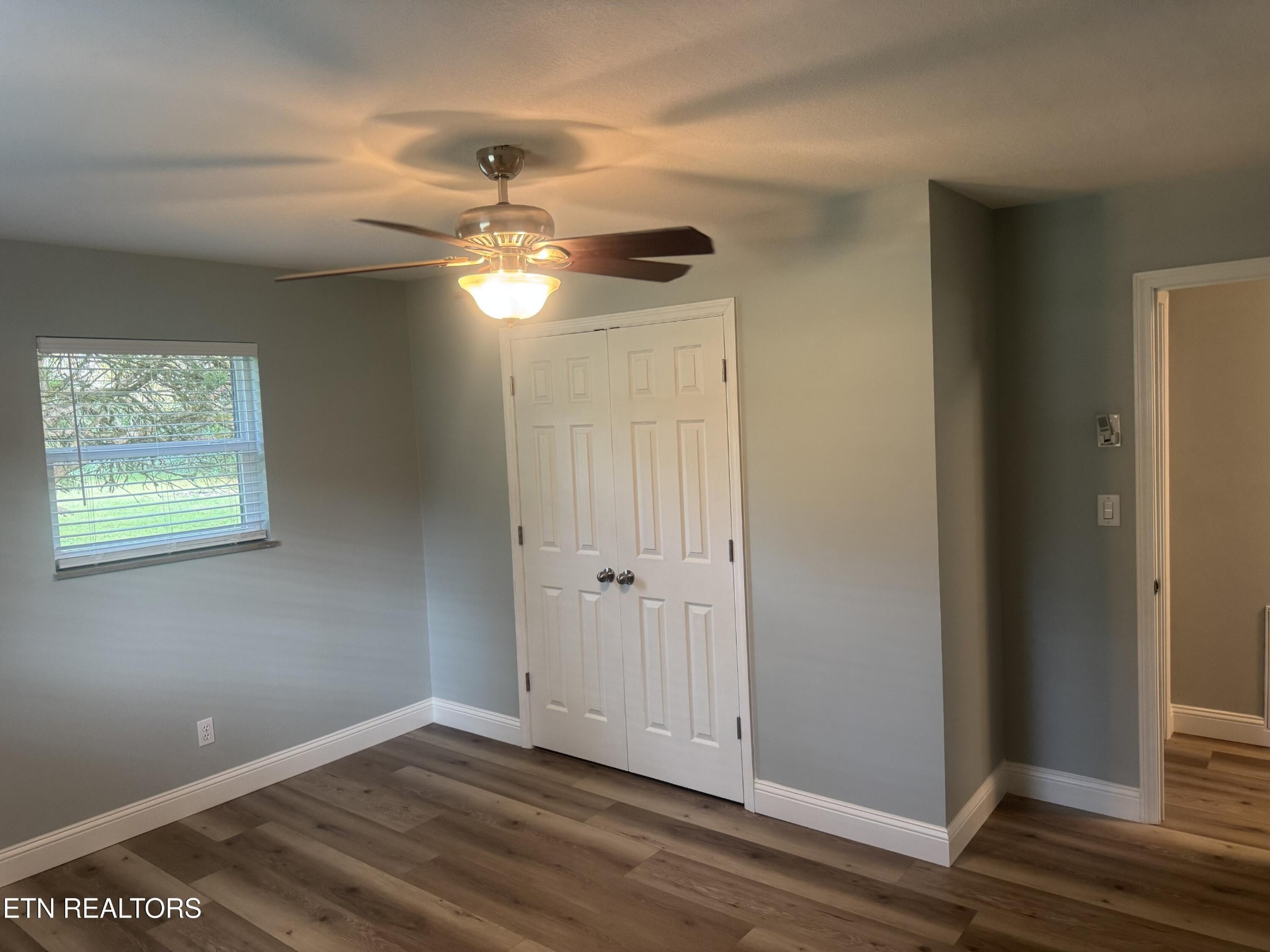 3341 West Wolf Valley Road Clinton, TN 37716 - Photo 29 of 41 an empty room with wooden floor chandelier fan and windows